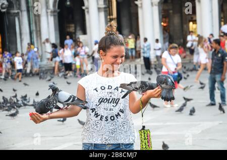 Ragazza con piccioni auf der Piazza san marco a venezia Stockfoto