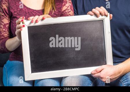 2 Personen mit leerem Schwarzen Brett und Holzrahmen. Freunde oder ein Paar, das eine leere Tafel mit Kopierbereich für den Hintergrund anzeigt. Stockfoto