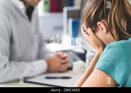Trauriger Patient, der den Arzt aufsucht. Junge Frau mit Stress oder Burnout, die Hilfe von medizinischen Fachärzten oder Therapeuten erhält. Angst, Depression. Stockfoto