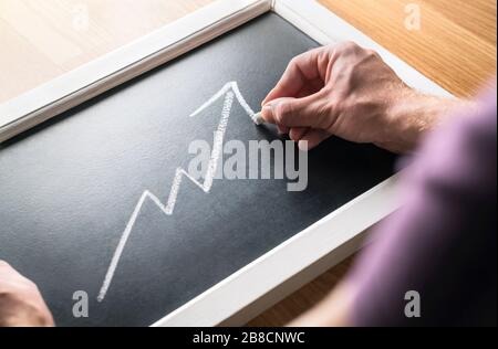 Wirtschaftswachstum. Prognose des steigenden Umsatzes oder Gewinns in der Wirtschaft. Bericht über die Finanzen. Erfolgreicher Business man zeichnet zunehmend Graph auf dem Schwarzen Brett. Stockfoto