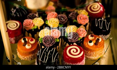 Nahaufnahme verschiedener süßer Cupcakes, selektiv fokussiert, vor einem bokehen Hintergrund. Stockfoto