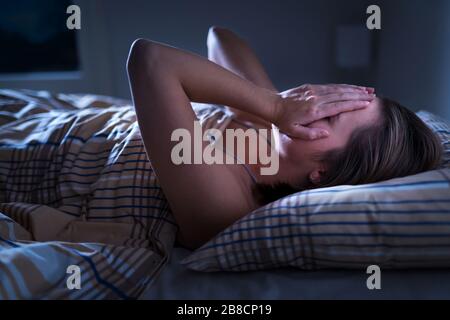 Schlaflosigkeit, Schlafapnoe oder Stresskonzept. Schlaflose Frau wach und bedeckt mitten in der Nacht das Gesicht. Dame kann nicht schlafen. Stockfoto