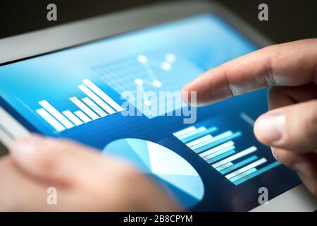 Statistiken, Diagramme, Trends und Wachstum auf dem Tablet-Bildschirm. Finanzmanagement und -Entwicklung mit Technologie im Geschäft. Geschäftsmann mit Monitor. Stockfoto