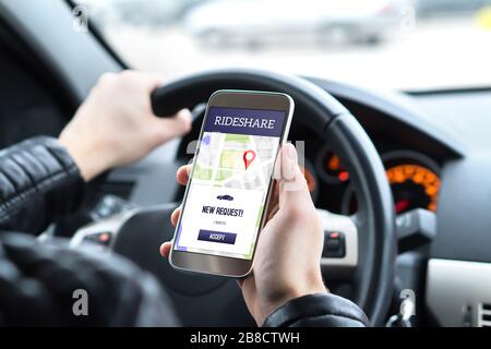 Fahren Sie mit der Rideshare-App auf dem Handy mit dem Fahrer im Auto. Neue Anfrage für Taxifahrten vom Kunden in Smartphone-Anwendung. Stockfoto