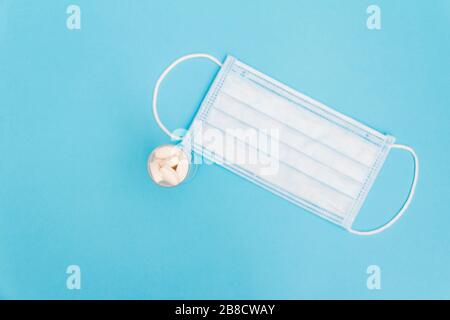 Coronavirus Konzept. Gesichtsmaske und Pillen auf blauem Hintergrund. Covid-19-Schutz. Stockfoto