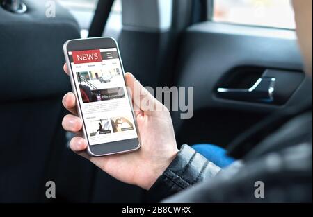 Person, die Online-Nachrichten mit dem Handy liest. Mockup der Zeitungswebsite auf dem Smartphone-Bildschirm. Mann genießt täglichen Pressedienst mit Handy im Auto. Stockfoto