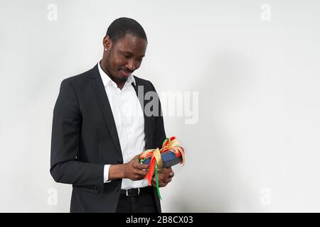 Junger afroamerikanischer Geschäftsmann, der Anzug mit Geschenk trägt. Dieses Konzept Stockfoto