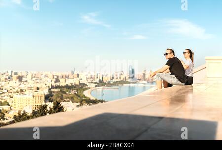 Touristen, die die Stadt Baku betrachten. Historische Altstadt und Boulevard Park im Hintergrund. Erkunden und besuchen Sie Aserbaidschan. Mann und Frau sitzen. Stockfoto
