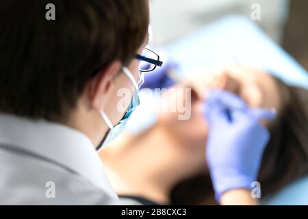 Zahnärztin oder Zahnarzthelferin in Betrieb mit dem Patienten. Frau mit Kalkül oder Karies. Mundarzt entfernt Weisheitszähne. Zahnmedizin. Stockfoto