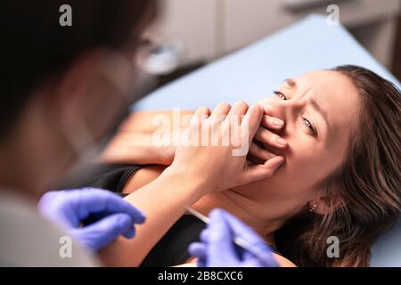 Angst vor Zahnärzten oder Angst vor Ärzten. Erschrockter und nervöser Patient im Krankenhaus. Fehlverhalten oder gefälschtes Ärztekonzept. Frau mit der Kobie verärgert. Stockfoto