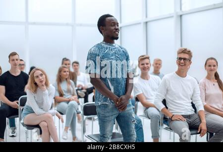 Lächelnder Kerl, der während des Seminars Fragen des Sprechers beantwortet Stockfoto