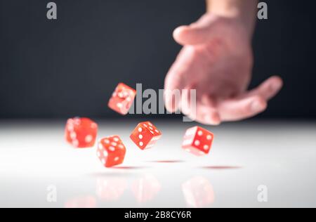 Handwerfen und Würfeln. Spieler werfen fünf rote Poker- und Casino-Würfel auf den Tisch. Man spielt oder spielt Brettspiel. Risiko, Glück, Wetten. Stockfoto