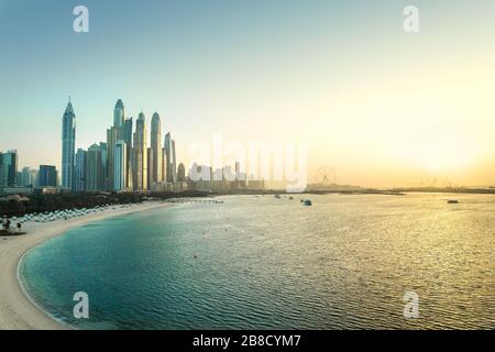 Dubai Marina bei Sonnenuntergang. Panoramablick auf Wolkenkratzergebäude, Strand, klaren Himmel und Meer im Morgengrauen. Malerische Skyline der Luxusstadt in den Vereinigten Arabischen Emiraten. Stockfoto