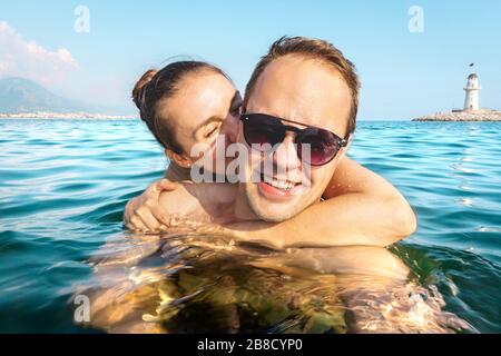 Paar, das selfie im Wasser nimmt, während er im Urlaub im Meer schwimmt. Zwei glückliche Leute im unterhaltsamen Familienurlaub. Romantische Flitterwochen im tropischen Sommer. Stockfoto