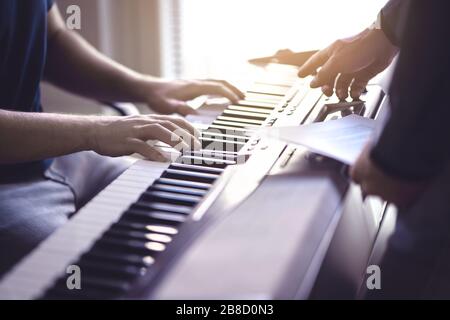 Musikunterricht und -Kurs. Klavierlehrer und Schüler, die in der Schule praktizieren. Man lernt mit Tutor im Unterricht spielen. Zwei Jungs trainieren. Mentor-Unterricht. Stockfoto