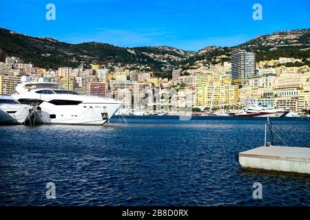Skyline von Monte Carlo mit Luxusyachten, die an einem sonnigen Tag im Hafen von Monaco verankert sind. Stockfoto