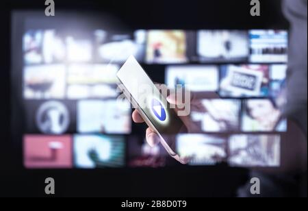 Movie-Stream-Smart-App auf dem Handy mit vielen Miniaturansichten von Online-Videoinhalten. Man sieht Serien mit Smartphone an. Futuristisches Hologramm. Stockfoto