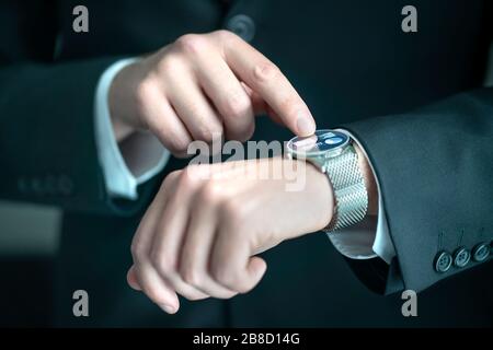 Geschäftsleute, die eine intelligente Uhr mit Bank-, Finanz- oder Business-Report-App tragen. Mann im Anzug mit tragbaren Geräten für die Arbeit. Hybrid-Smartwatch. Stockfoto