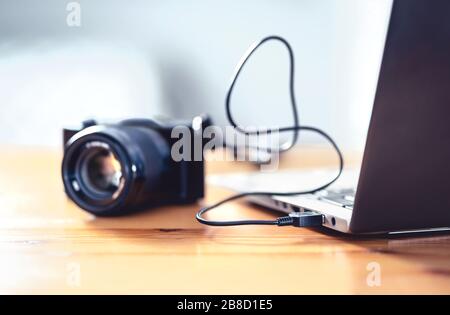 Kamera mit usb-Kabel an Laptop angeschlossen. Dateiübertragung von DSLR auf den Computer. Sichern Sie die Speicherung für Fotos. Stockfoto