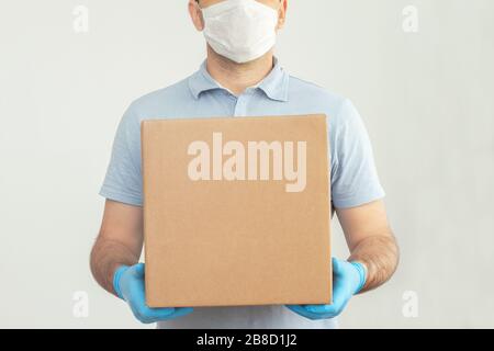 Lieferer, der Kartons hält.Zustellung per Kurier in medizinischen Gummihandschuhen. Die Versandzeit während des Coronavirus. Quarantäne Stockfoto