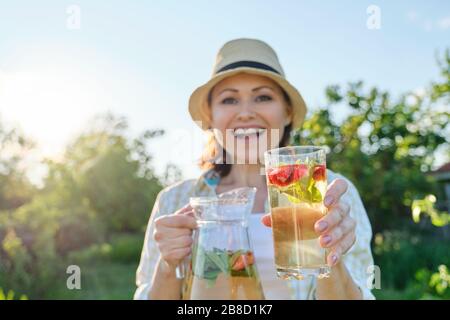 Frühlingssommer-Erfrischungen, Frau in der Natur, die einen Krug mit Erdbeerminze und Zitrone hält, kalte Erfrischungsgetränke, gesunde, hausgemachte Vitamingetränke Stockfoto