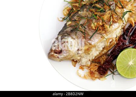 Gebackene Fische schmackhaft gebraten (Pla som tod: thailändisches Wort), gebackene Fischbraten und gebratene Zwiebeln, Limettenscheibe und gebratene Chili mit frischem Gemüse auf Weiß serviert Stockfoto