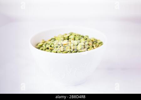 Trocken gespaltene hellgrüne Erbsen in einem weißen Becher Stockfoto