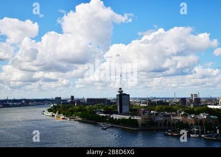 Hoch über dem Blick auf die Maas, mit Schiffen, die an einem sonnigen Tag in Meeresrichtung schwimmen, mit weißen Wolken hoch oben am Himmel und den symbolträchtigen Gebäuden Vis Stockfoto