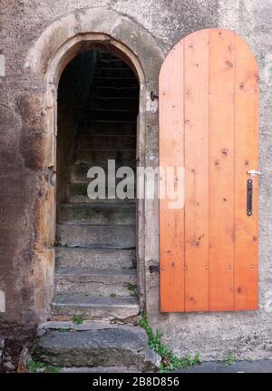 Schmale Bogenform steinerne Wandeinfahrt und Treppe mit Holztür. Stockfoto