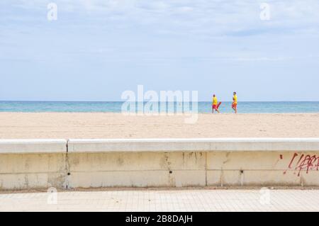 Zwei Rettungsschwimmer im Dienst und in Uniform gehen auf einer verlassenen Platja del Fòrum im Norden von Barcelona, Spanien Stockfoto