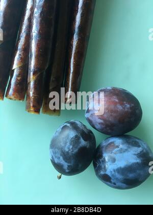 Süße pürierte Fruchtpastille. Auf Holzgrund hausgemachte Obstaufrollungen. Natürliche Süßigkeiten aus Pflaumenfrüchten. Stockfoto