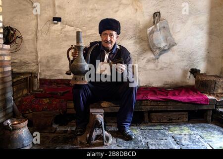 Ältere lokale Handwerker Herstellung metallischen Gläser für das Kochen Tee in seiner Werkstatt, Chiva, Usbekistan Stockfoto