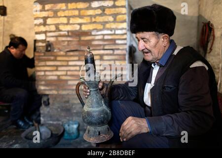 Lokaler Handwerker und sein Sohn machen Metallgläser für das Kochen von Tee in seiner Werkstatt, Chiva, Usbekistan Stockfoto