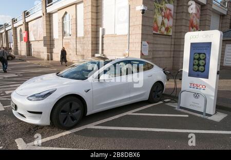 Ein Tesla-Elektroauto, das an einem Tesco Pod Point in Edinburgh, Großbritannien aufgeladen wird. Stockfoto