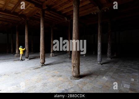 Usbekistan, Khiva, Junge in gelber Jacke mit Blick auf die geschnitzten Details der Holzsäulen in der alten Juma-Moschee Stockfoto