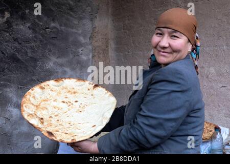 Eine lokale Frau backt traditionelles Brot in EINEM traditionellen Lehmofen, Khiva, Usbekistan Stockfoto