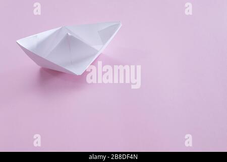 Weißes Papier handgefertigtes Origami-Boot auf dem rosafarbenen Hintergrund. Kopieren Sie Speicherplatz für Ihren Text. Thema hausgemachtes Spielzeug für Kinder. Stockfoto