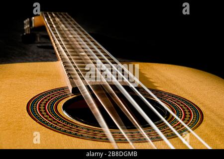 Klassische Gitarre mit vibrierenden Saiten auf schwarzem Hintergrund Stockfoto