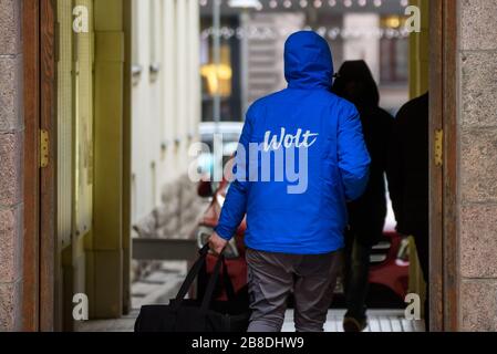 RIGA, LETTLAND. November 2019. Lebensmittel-Lieferarbeiter der Firma Wolt spazieren mit Lebensmittelbeutel in Rigaer Stadt. Wolt ist ein finnisches Technologieunternehmen, das für seine Lebensmittel-Lieferplattform bekannt ist. Stockfoto