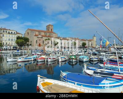 Vieux Port aka alten Hafen in einer mediterranen Stadt La Ciotat in Südfrankreich mit vielen angedockten kleinen Booten und der Hauptkirche der Stadt Stockfoto