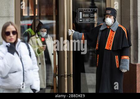 Moskau, Russland. März 2020 EIN Türsteher und Besucher in einer medizinischen Maske in der Nähe des Haupteingangs im TSUM-Laden der Innenstadt Moskaus während der Epidemie des COVID-19-Coronavirus Stockfoto