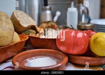 Stillleben von biologischem und frischem Naturgemüse. Kartoffeln, Tomaten, Zitrone, Brot, Harina, Pilze, Gemüse und einige Küchentöpfe im Backg Stockfoto