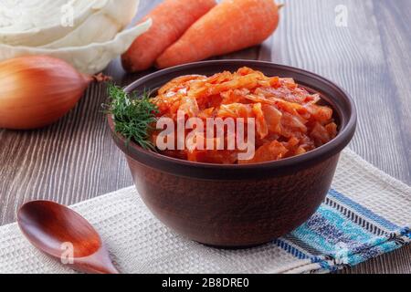 Geschmorter Kohl mit Tomaten auf altem Holzhintergrund im rustikalen Stil Stockfoto