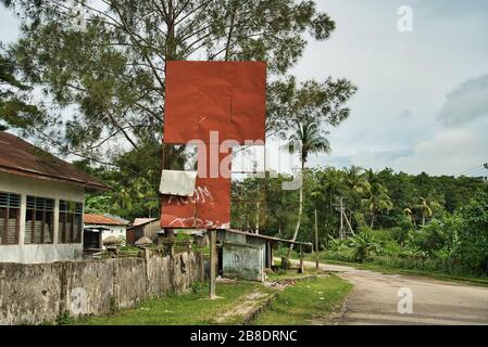 Alte, unvollständige und baufällige rote Plakattafel aus Terrakotta, frei von Werbung auf einer überfüllten Straße in einer Dschungelstadt. Stockfoto