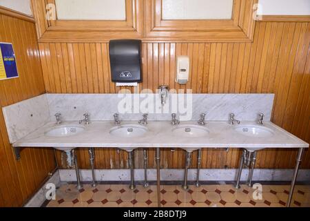 Marmorwaschbecken und Holzvertäfelung in einer öffentlichen Toilette Stockfoto