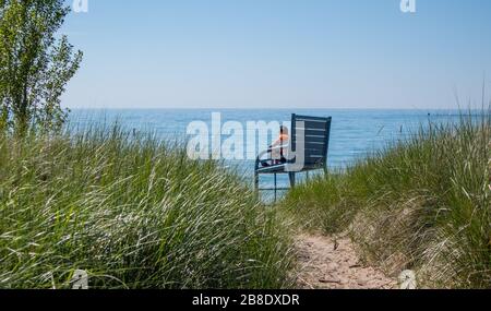 Auf einer überdimensionalen Bank am Strand in Kincardine sitzt ein Mann weit in die Ferne. Stockfoto