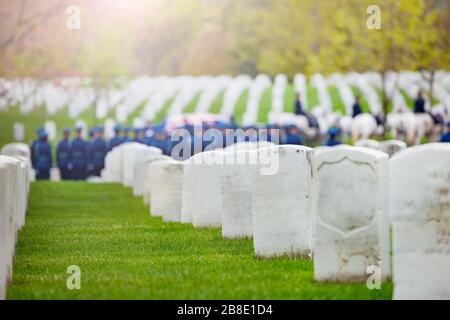 Militärfriedhof und Grabzug im Hintergrund, Reihen weißer Grabsteine mit Soldaten in Uniform Stockfoto