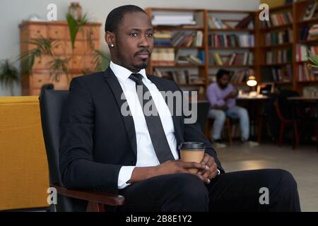 afroamerikanischer Geschäftsmann mit Kaffee in einem Hotelcafé Stockfoto