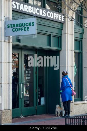 Washington, USA. März 2020. Eine Frau liest ein Schild, in dem angekündigt wird, dass die Schließung des Stores am 21. März 2020 im Fenster eines Starbucks in der M Street in Washington, DC, veröffentlicht wird. Starbucks kündigte heute an, dass die nächsten zwei Wochen nur Café-Geschäfte geschlossen werden und der Drive-Thru-Betrieb weiterhin geöffnet bleiben wird. (Foto von Leigh Vogel/Sipa USA) Kredit: SIPA USA/Alamy Live News Stockfoto