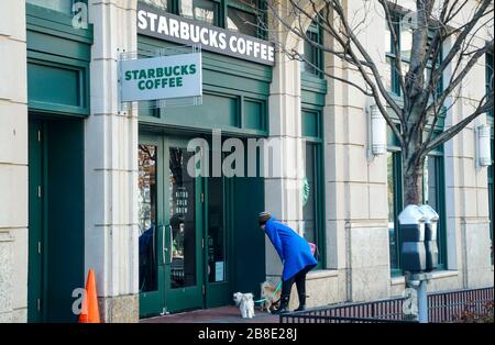 Washington, USA. März 2020. Eine Frau liest ein Schild, in dem angekündigt wird, dass die Schließung des Stores am 21. März 2020 im Fenster eines Starbucks in der M Street in Washington, DC, veröffentlicht wird. Starbucks kündigte heute an, dass die nächsten zwei Wochen nur Café-Geschäfte geschlossen werden und der Drive-Thru-Betrieb weiterhin geöffnet bleiben wird. (Foto von Leigh Vogel/Sipa USA) Kredit: SIPA USA/Alamy Live News Stockfoto